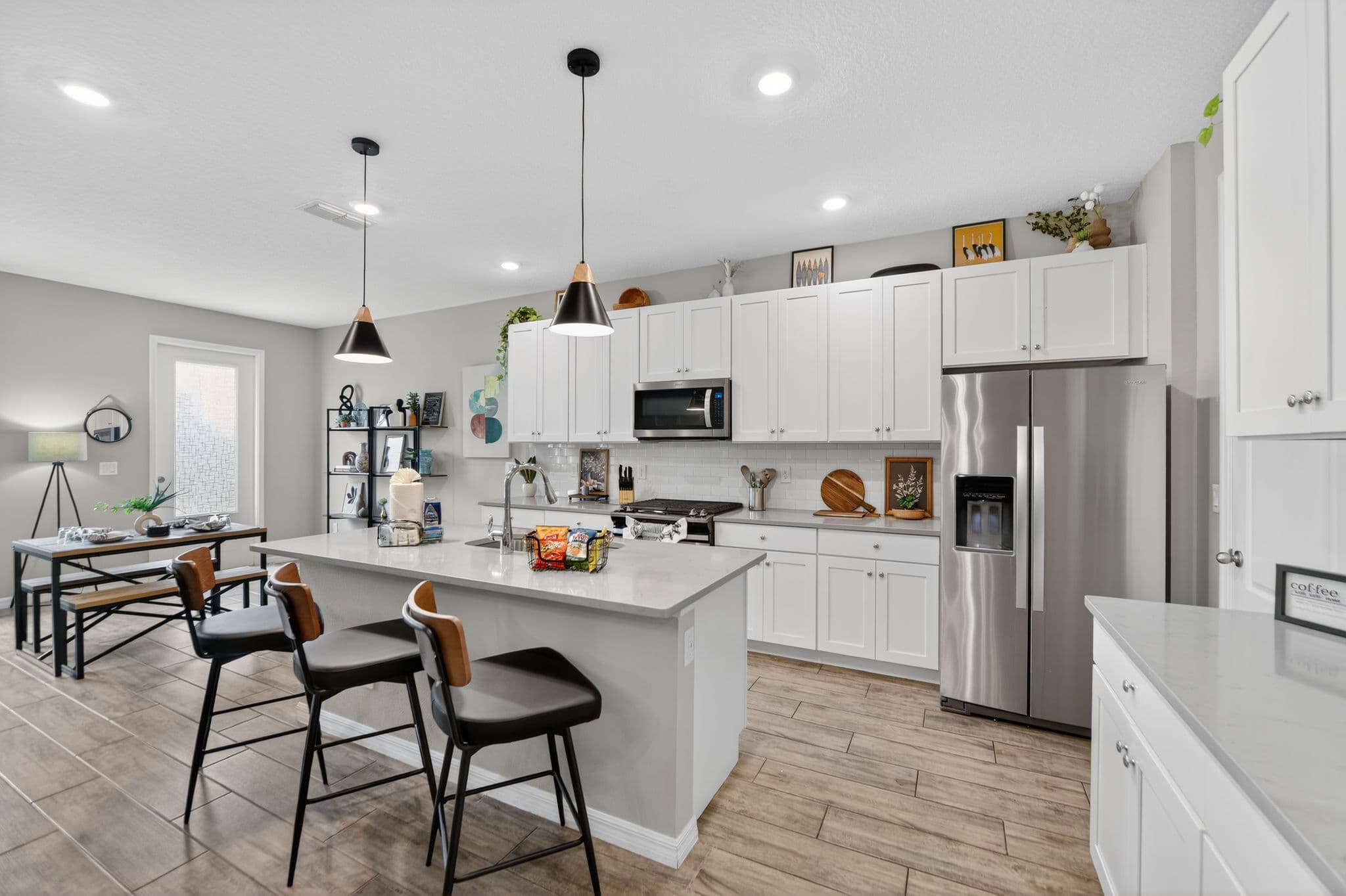 Modern kitchen with white cabinets, stainless steel appliances, and a large island with black stools.