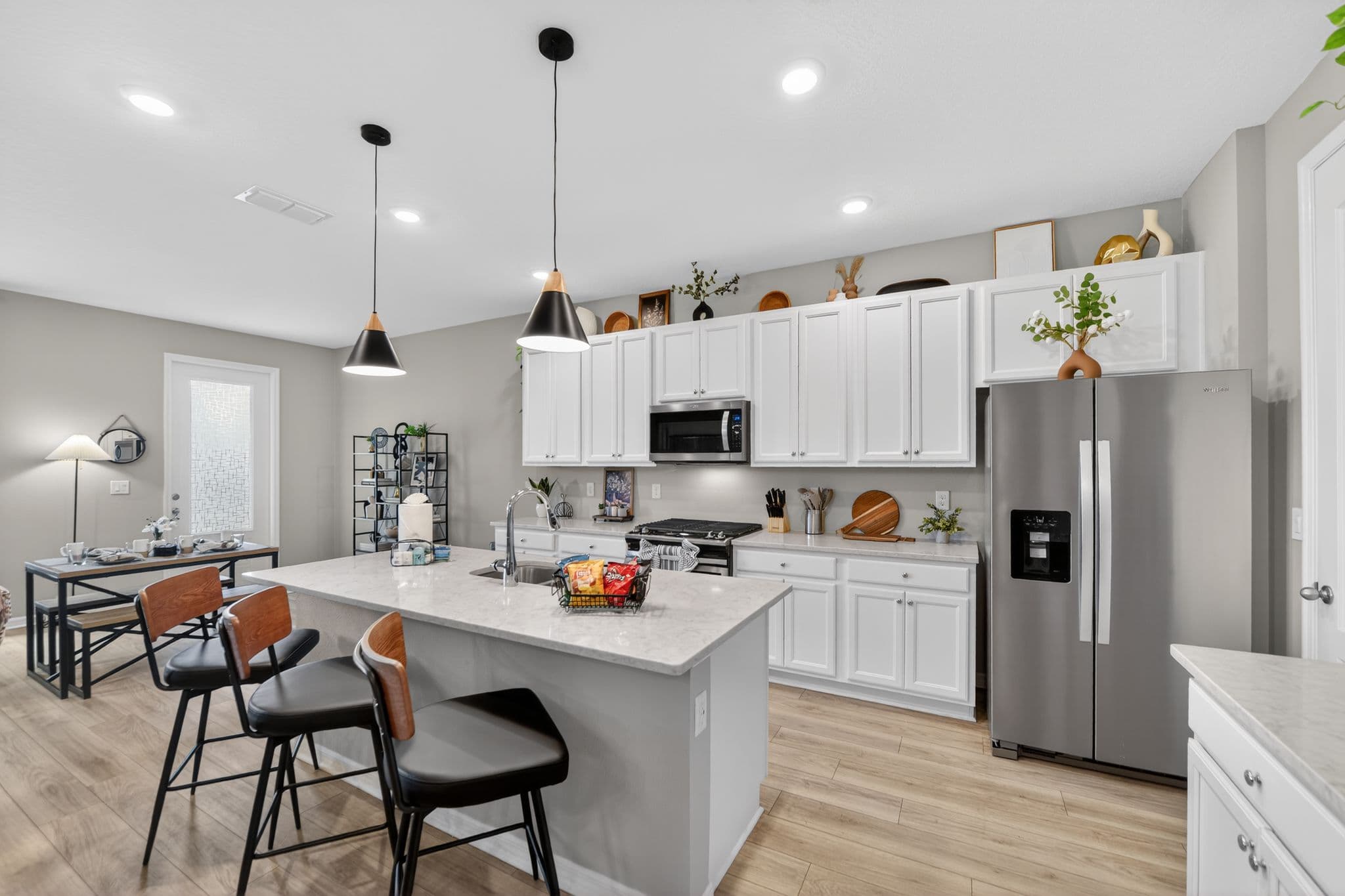 Modern kitchen with white cabinets, marble island with bar stools, and stainless steel appliances.