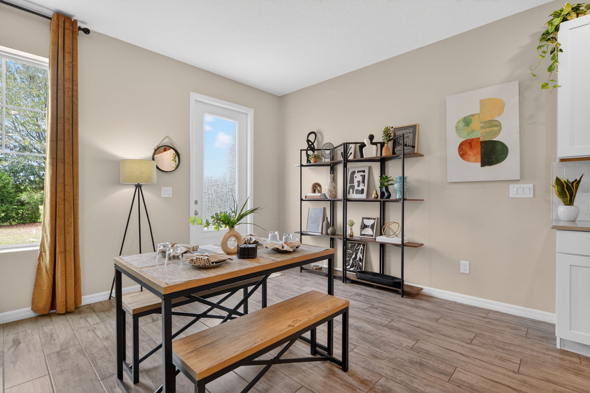 Modern dining room with wooden table, benches, black metal shelving unit, and abstract wall art.