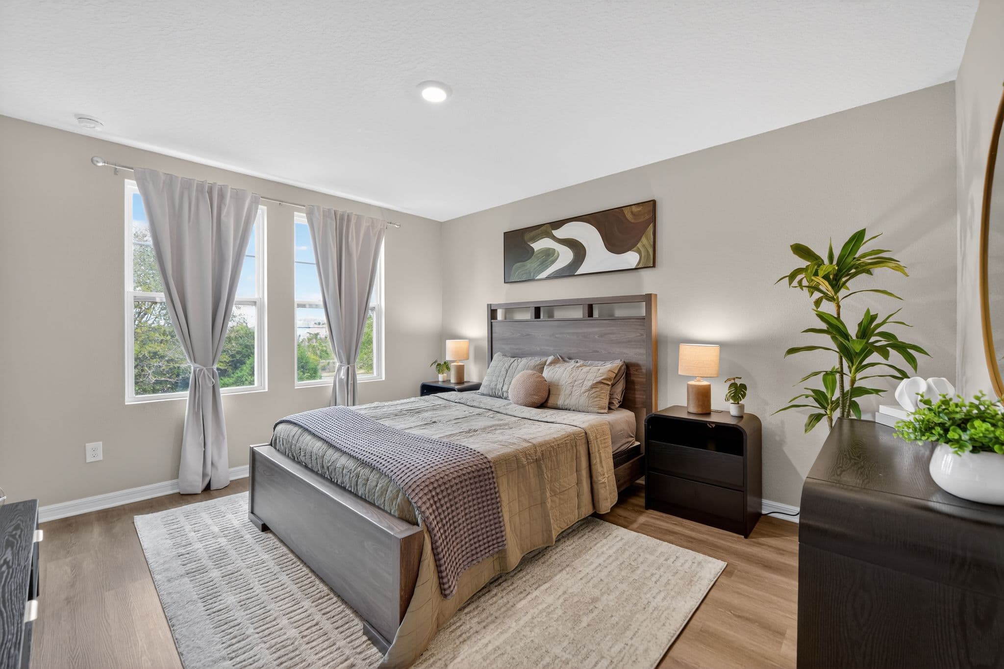 Modern bedroom with dark wood bed frame, grey curtains, abstract art, and neutral-toned decor.